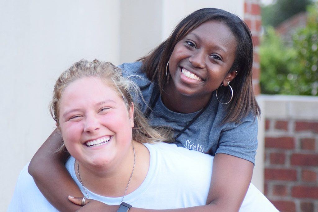 Two college-aged girls pose smiling